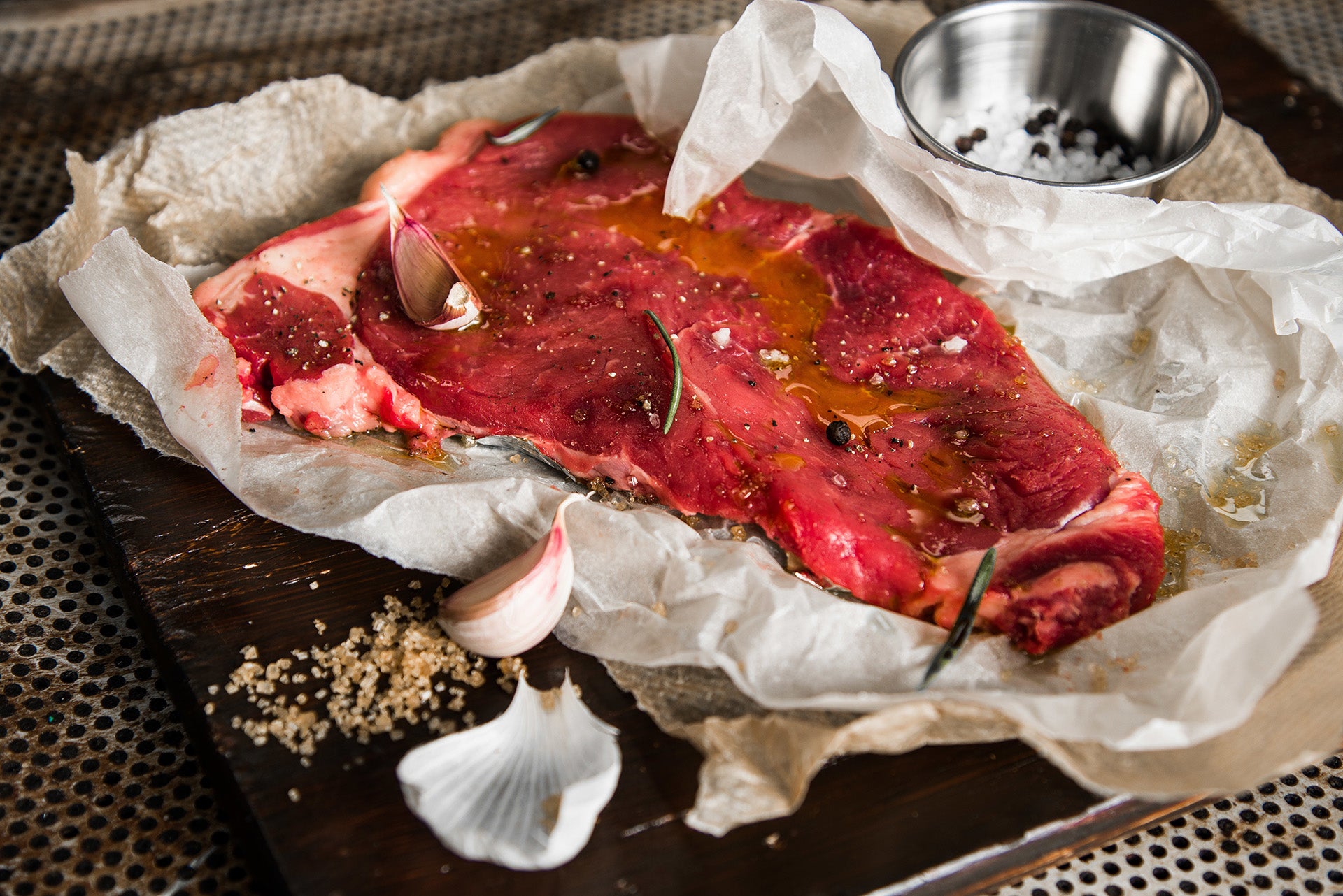 Raw meat pieces on wooden cutting board with oil, spices, marinade